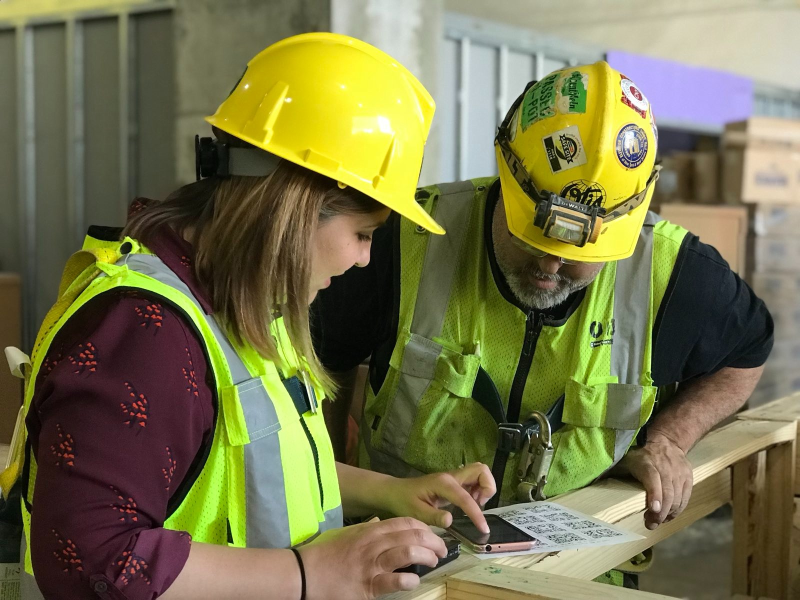 Woman and man on a construction site testing a QR code scanning phone app